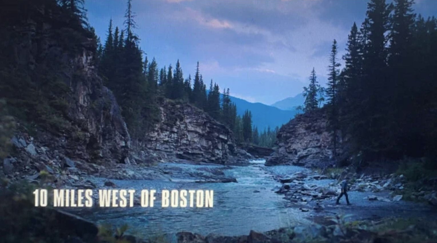A creek with mountains in the background and a caption that says "10 miles west of Boston"