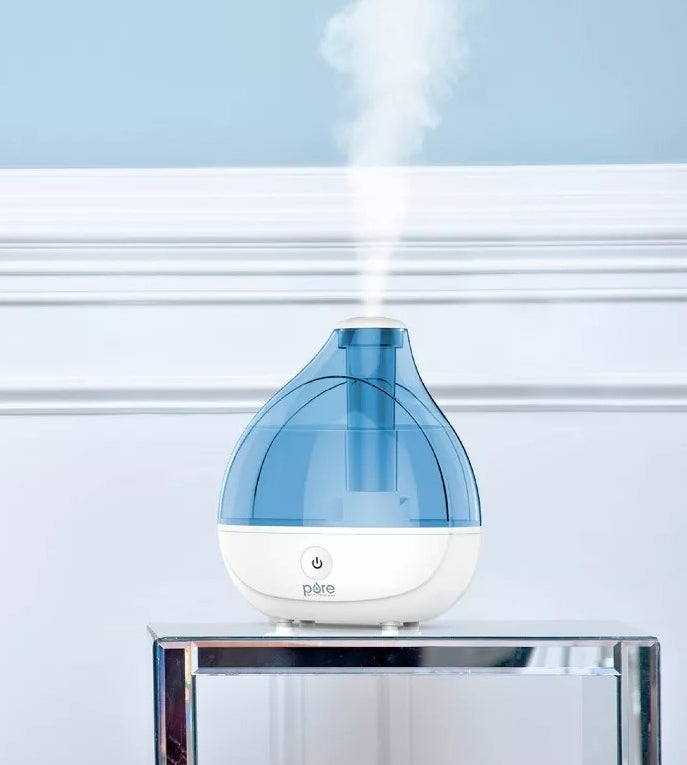 Blue and white plastic humidifier emitting vapor