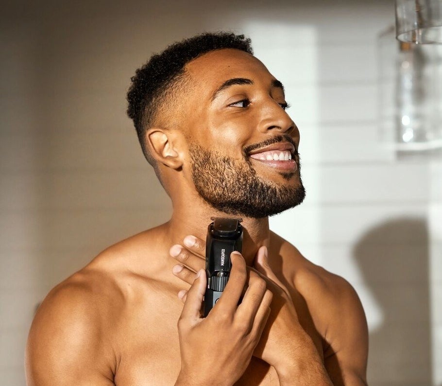 a smiling person using the trimmer to shave their beard