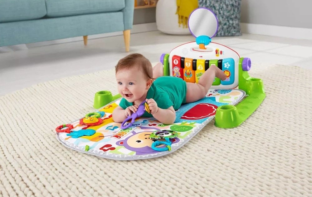 Baby model on belly on floor atop of colorful play may gym
