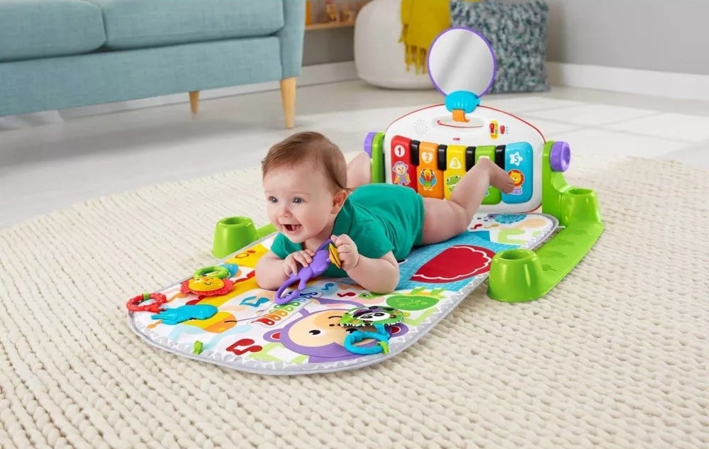 Baby model on belly on floor atop of colorful play may gym