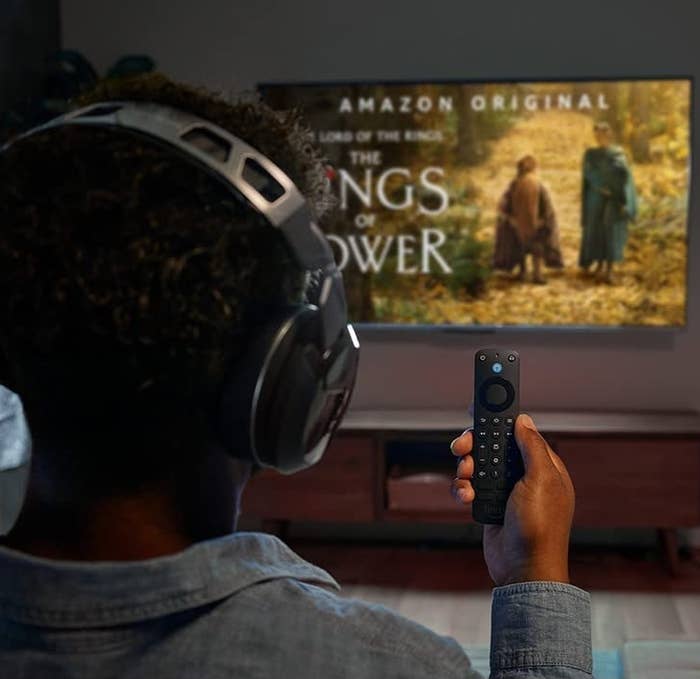 a person holding the voice remote pro while watching lord of the rings