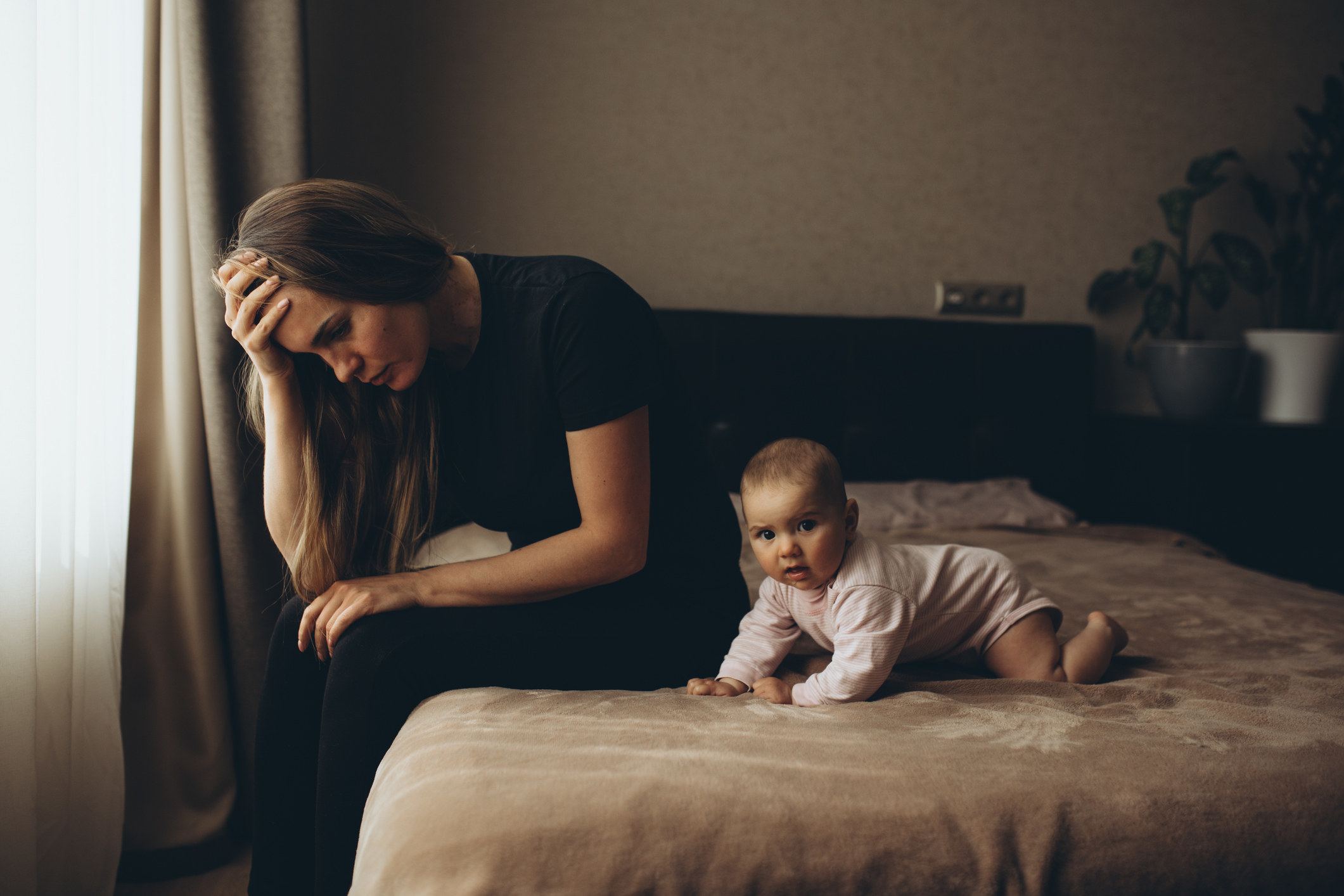 mom stressed with baby on bed