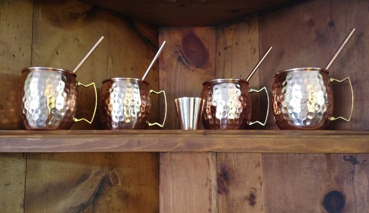 The four mugs with straws and a shot glass on a reviewer&#x27;s shelf