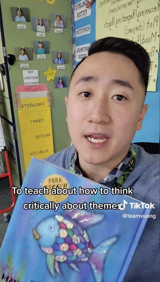 Screenshot of TikTok from user @teamvuong of Mr. Vuong holding a copy of Rainbow Fish