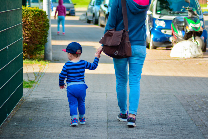A woman walking with her child on the sidewalk