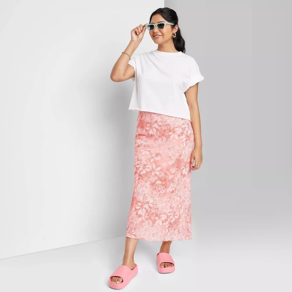Model wearing pink and white floral midi skirt with white crop top