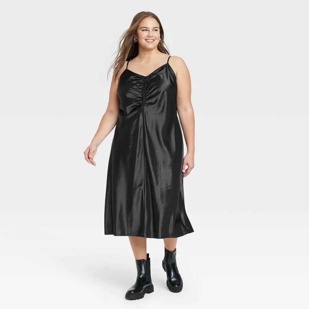 Model wearing black slip dress with black booties