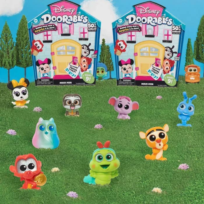 several of the mini figurines on a lawn in front of the door-themed packaging