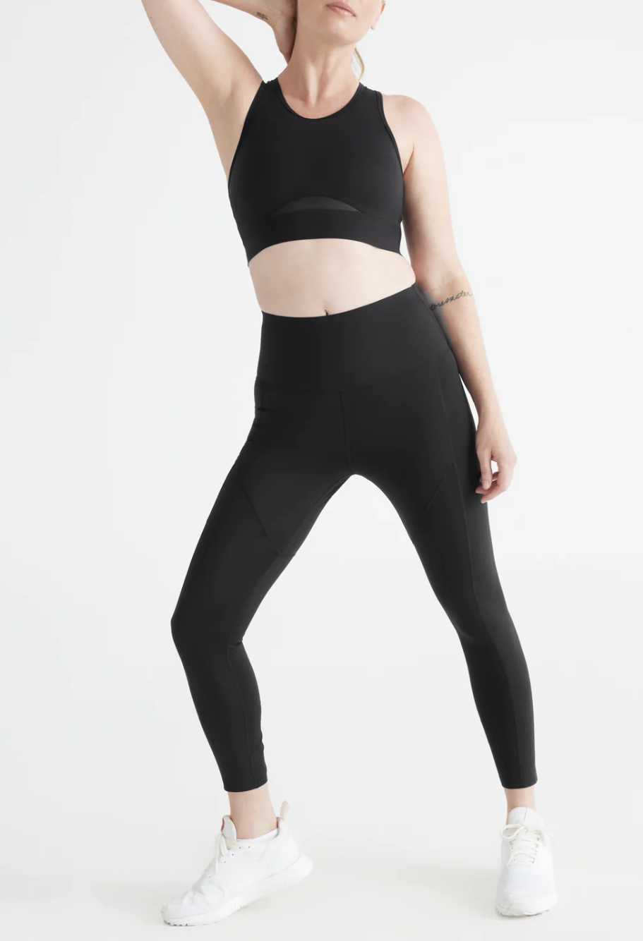 a model wearing the leggings with a sports bra in front of a plain backdrop