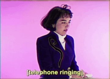 woman dressed in 80s business casual clothing holding a landline phone to her ear and saying sorry destiny is calling