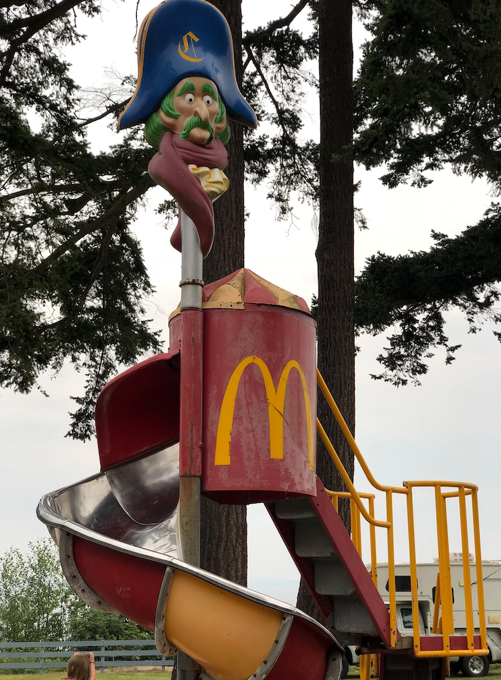 red and yellow metal slide with pirate head on top