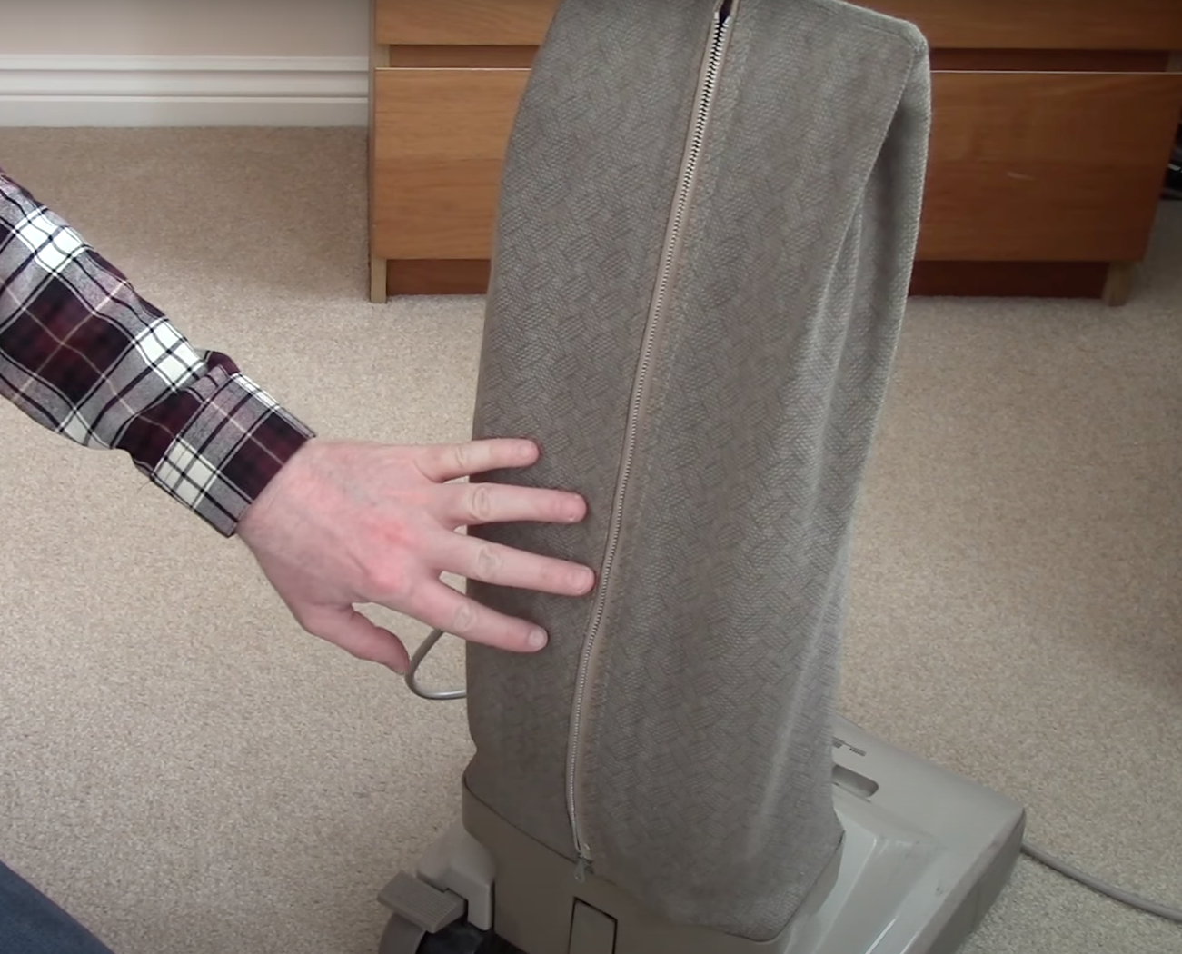 Screen shot of hand touching back of upright vacuum bag