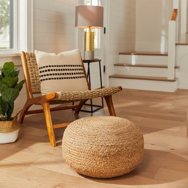 woven jute pouf on hardwood floors next to a chair
