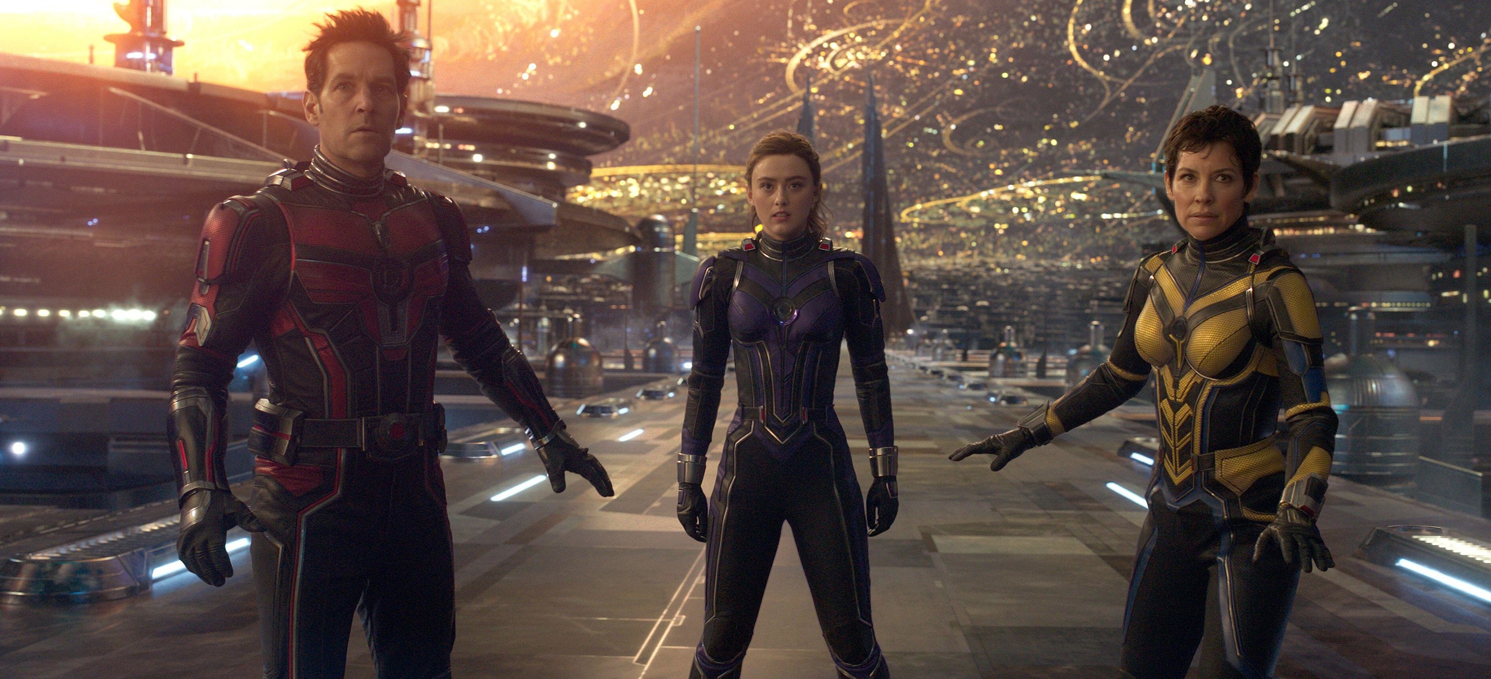 A trio of superheroes stand pensively on a futuristic walkway