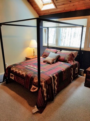 Reviewer's black canopy bed is shown