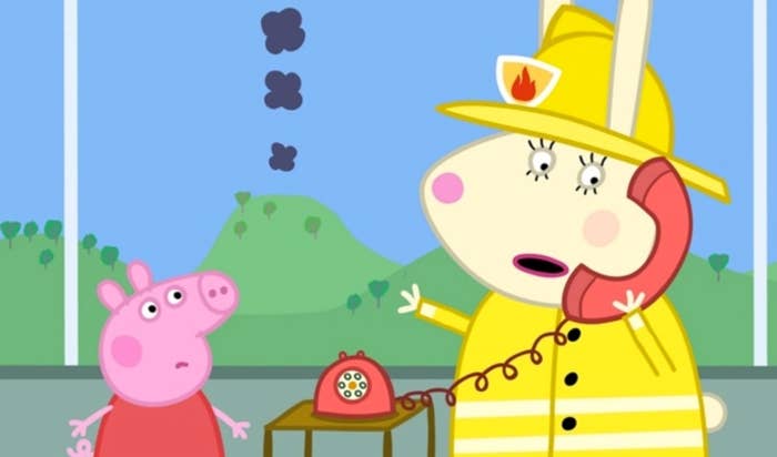 peppa pig looks up at an adult animated rabbit who wears a firefighter&#x27;s outfit and talks on the phone