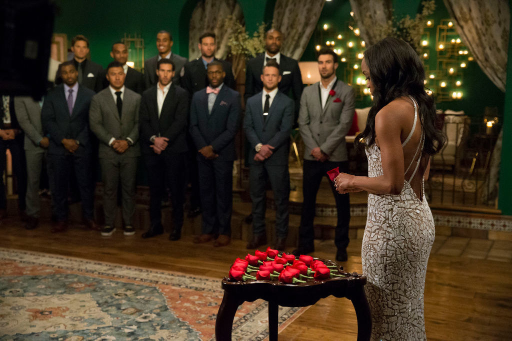 Scene from the show with the Bachelorette standing in front of a table with roses