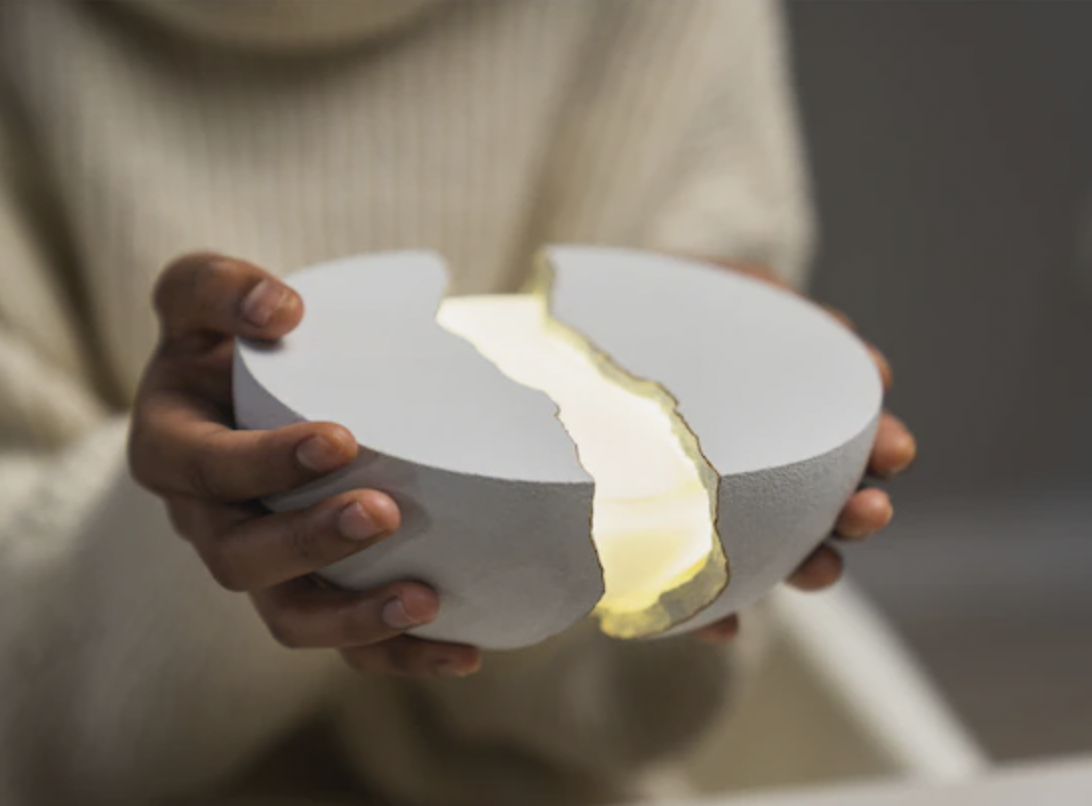 a person holding up a light speaker duo that looks like a cracked sculpture