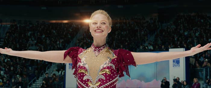 Margot as figure skater Tonya Harding with her arms raised as she acknowledges the crowd from the middle of the ice