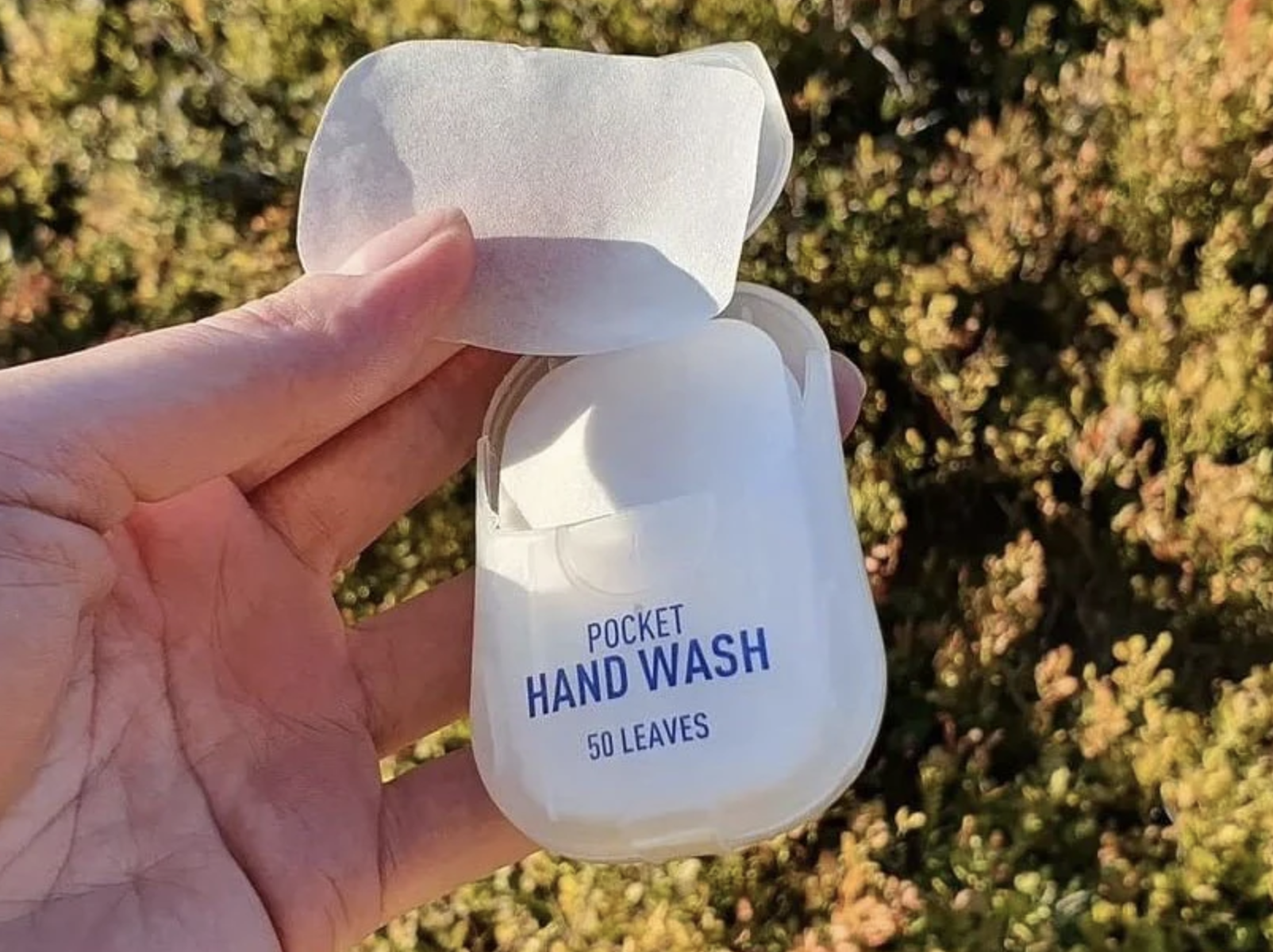 a person lifting one of the soap leaves out of the packaging