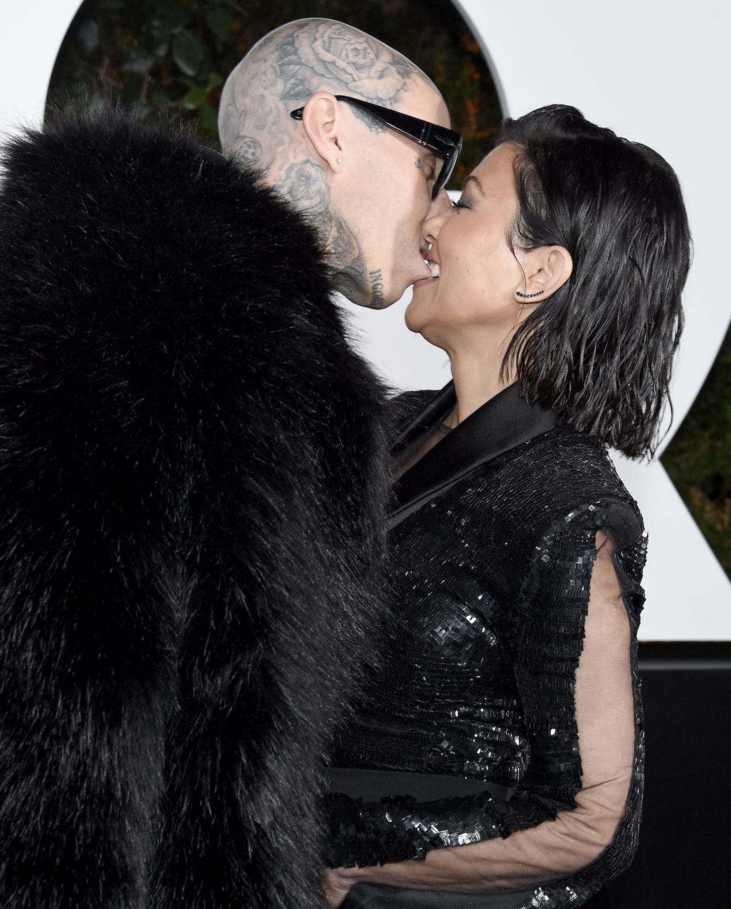 Kourtney playfully biting Travis&#x27;s bottom lip as they embrace each other at an event