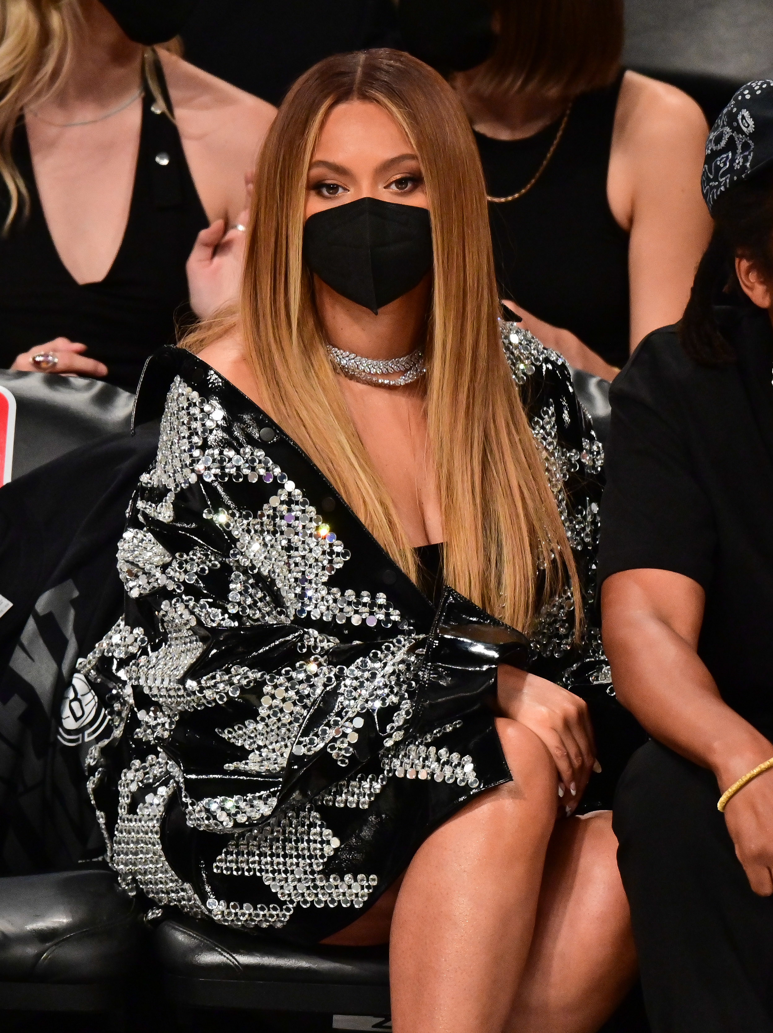 Beyoncé wears a face mask and a sequined jackets as she sits in the front row