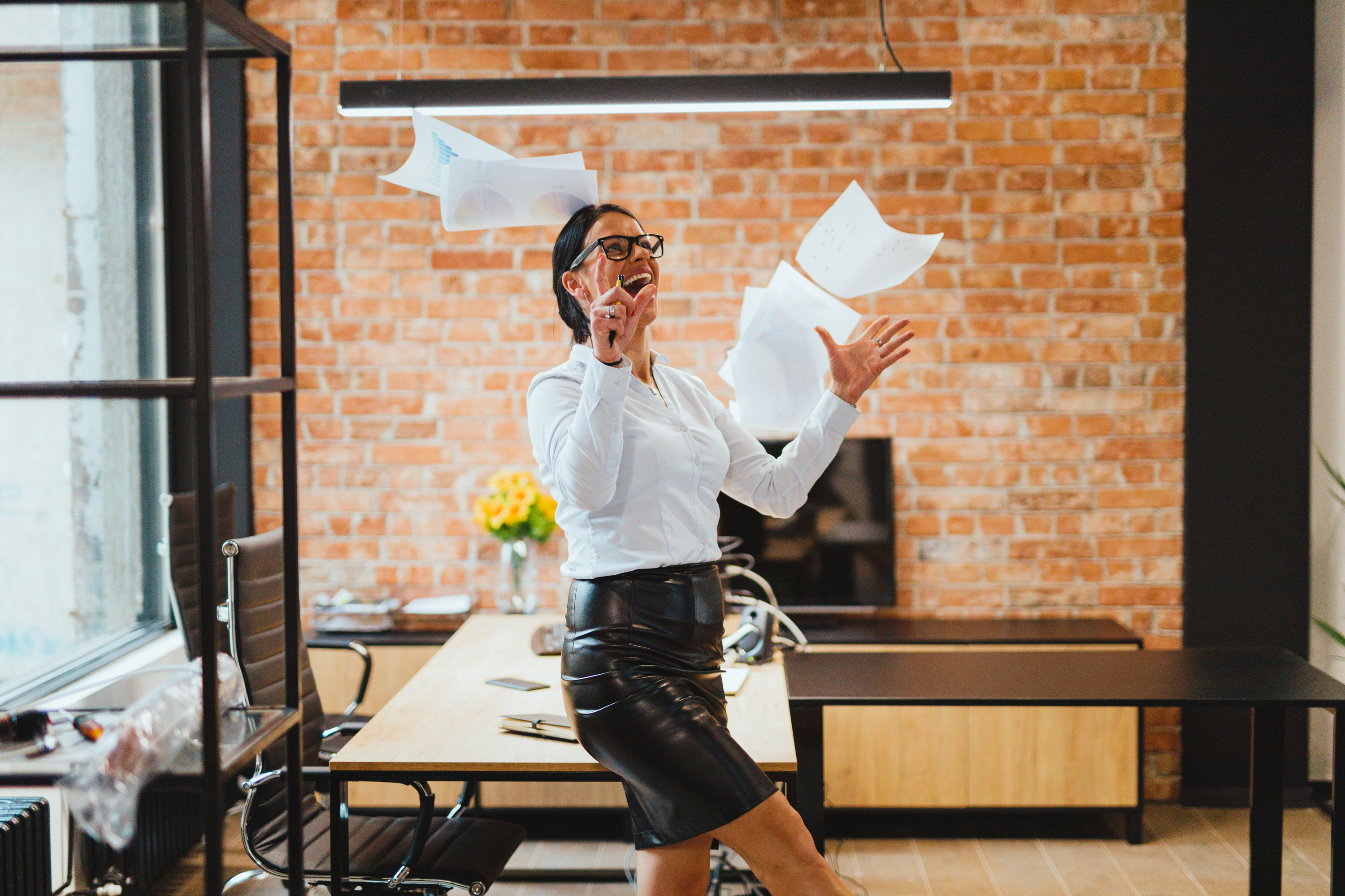 Happy woman in an office throwing paperwork in the air