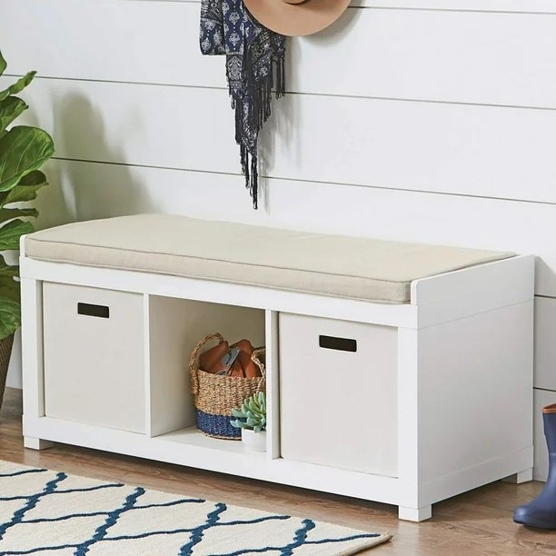 a white three-cube storage bench with cubbies and a plant