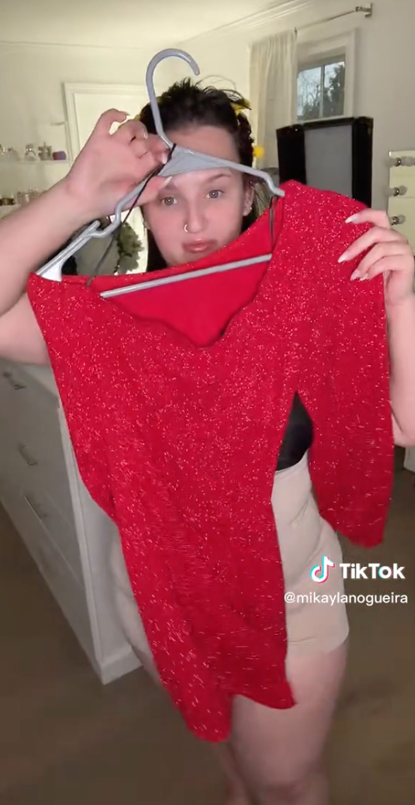 Mikayla holds up a short dress with three-quarter sleeves