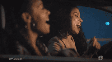 Two women dancing and singing to music in the car