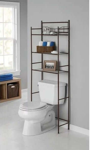 a black three-shelf bathroom mainstay above a toilet and holding toiletries