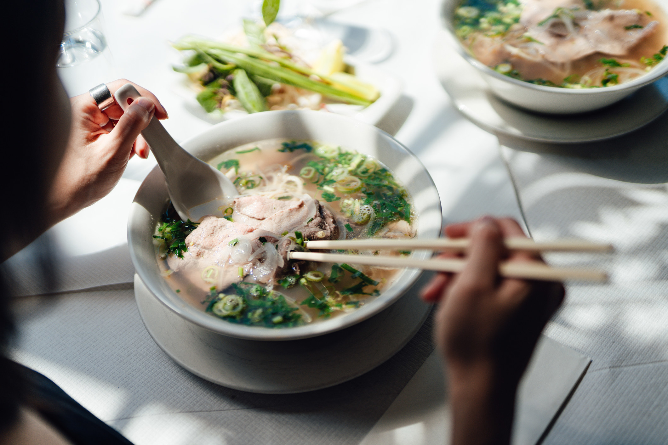 Person eating a bowl of pho
