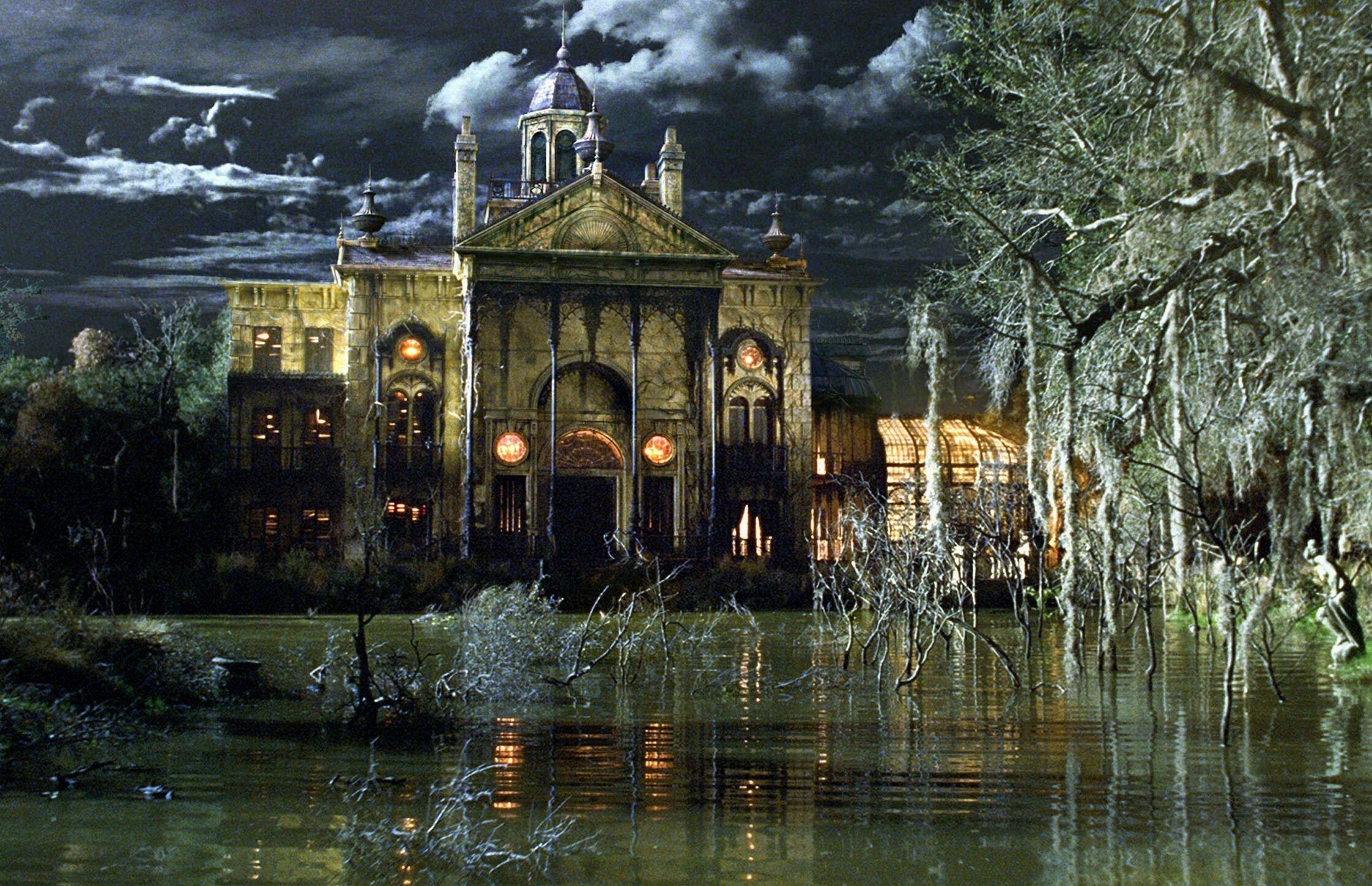 A spooky mansion stands bright in a New Orleans swamp at night