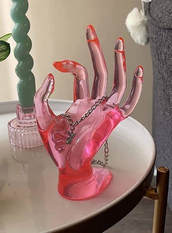 Reviewer's neon pink plastic hand is shown holding jewelry