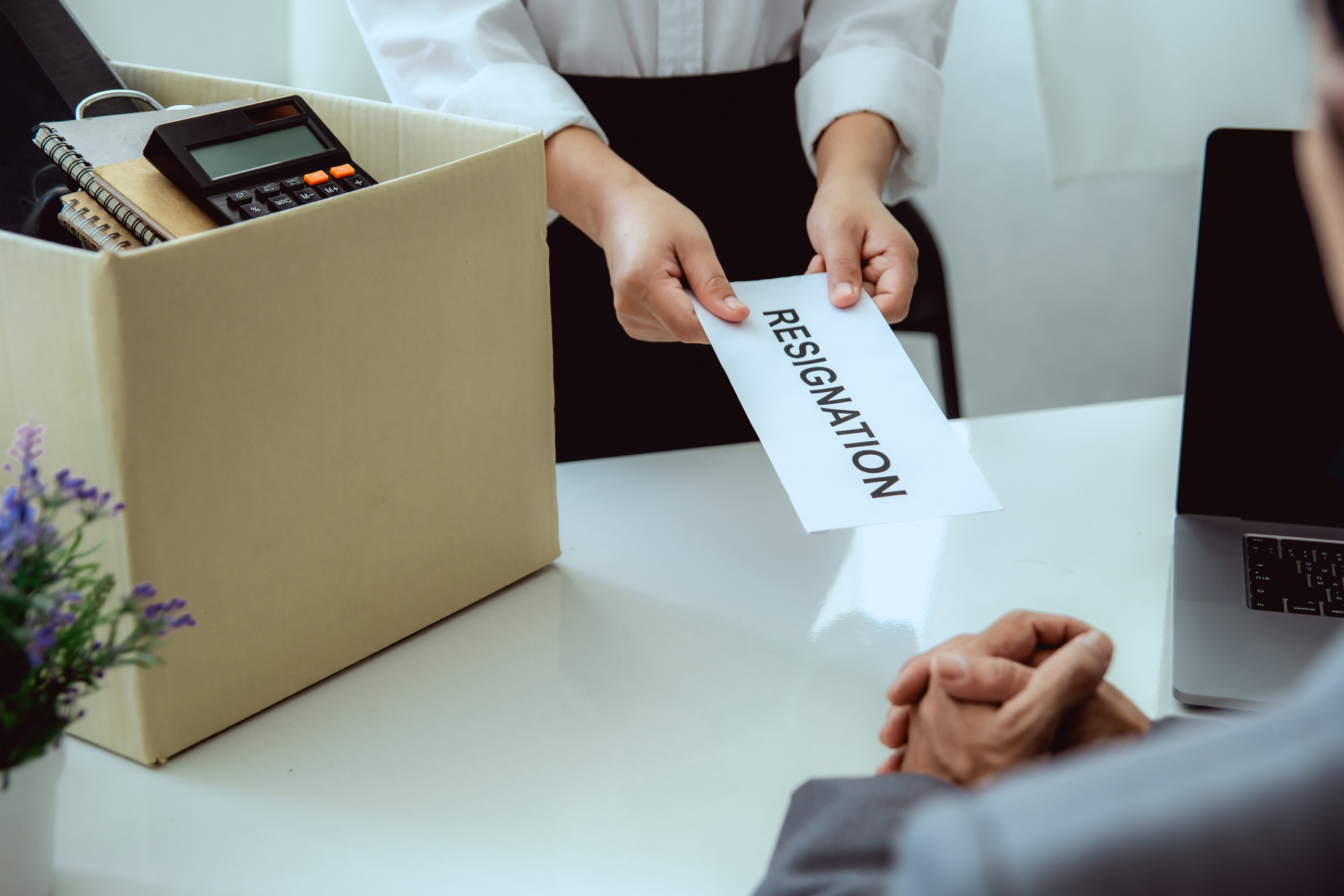 Person handing their boss an envelope marked &quot;Resignation&quot;