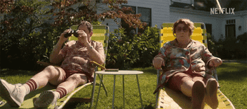 A couple sitting on lawn chairs in a yard.