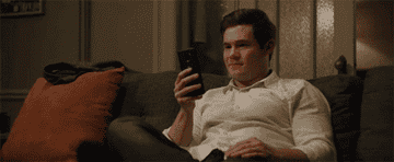 A man sitting on a couch looking at his phone