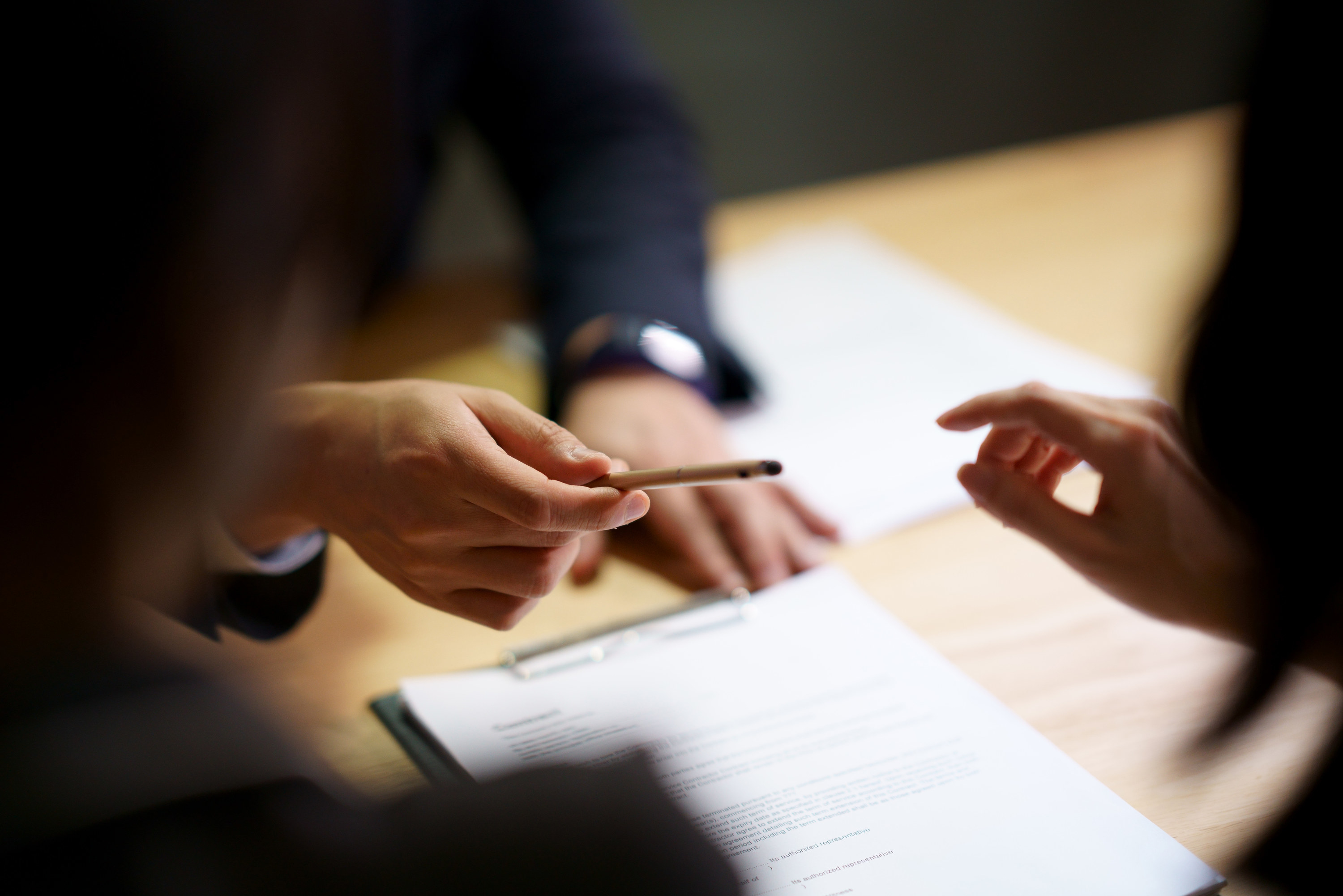 people passing a pen to sign a contract