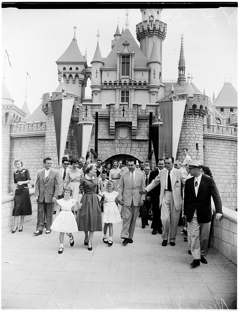nixon and family walk with walt disney and a crowd in the park