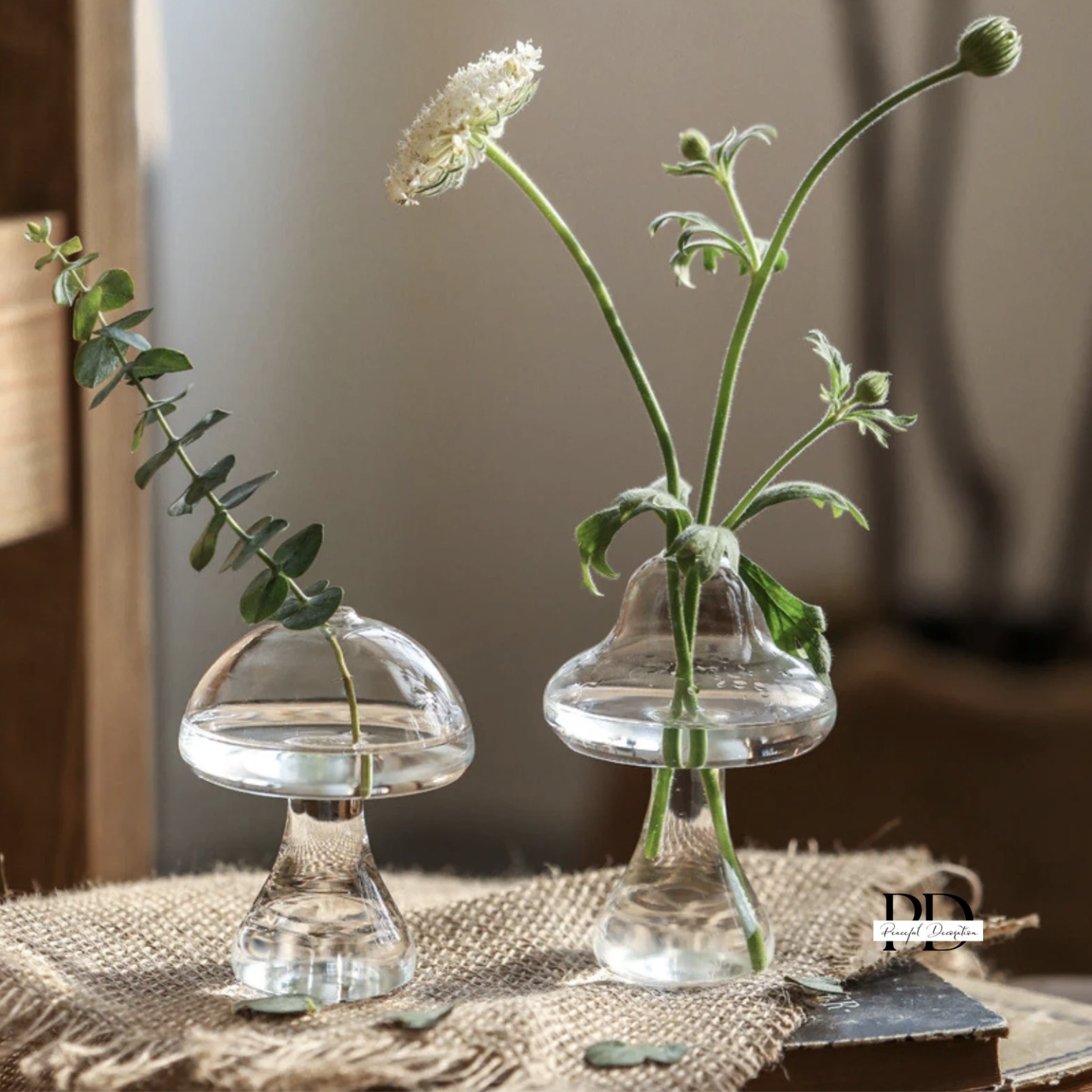Two mushroom vases with plant clippings in them