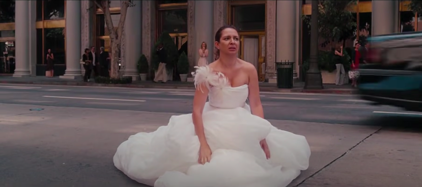 A woman in a wedding dress sits in the middle of the street