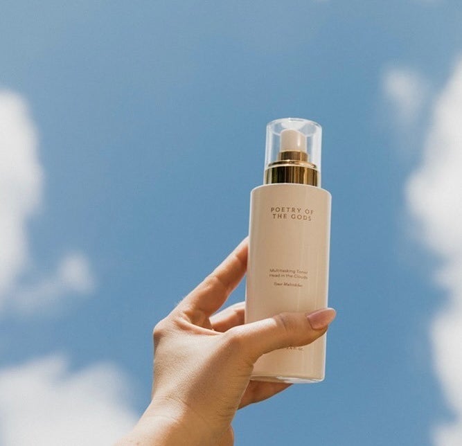 someone holding up a bottle of the toner against a bright daytime sky