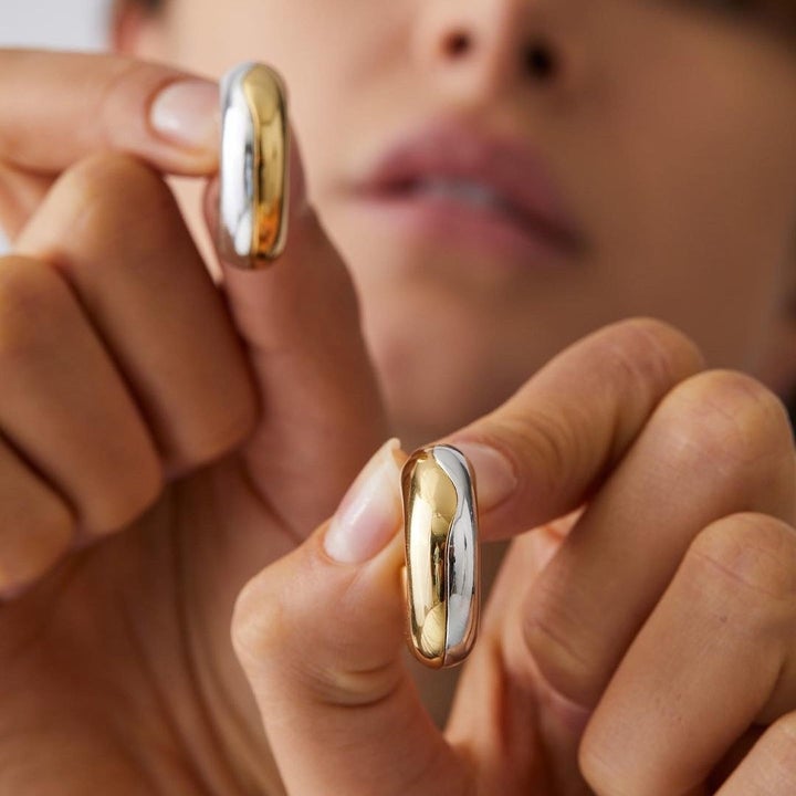 a person holding up the hoops to show off the dual toned metals