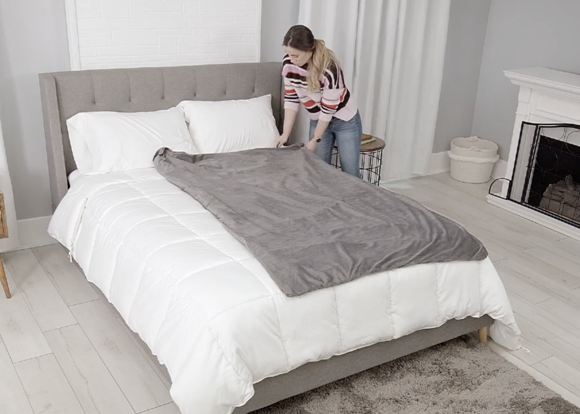 model putting the gray blanket on a bed