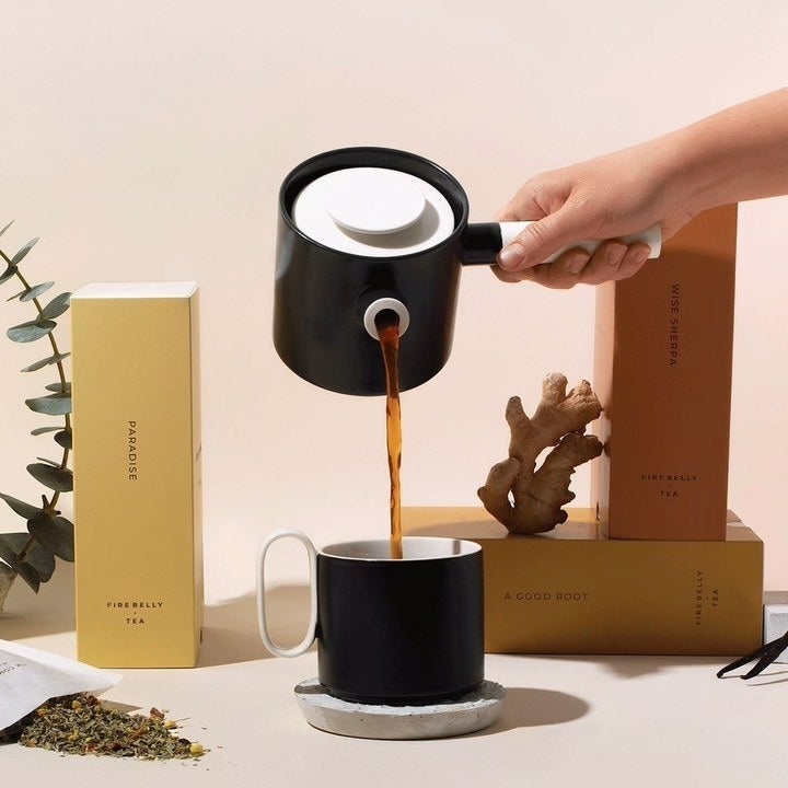 someone pouring tea out of the ergonomic teapot into a mug