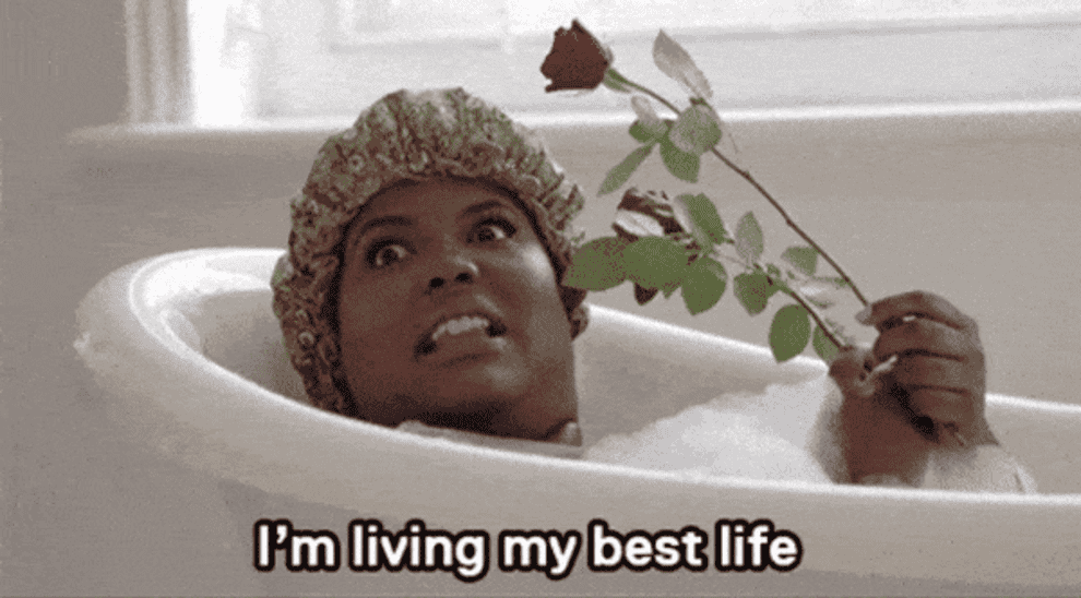 person in a bubble bath holding a rose saying &quot;I&#x27;m living my best life&quot;