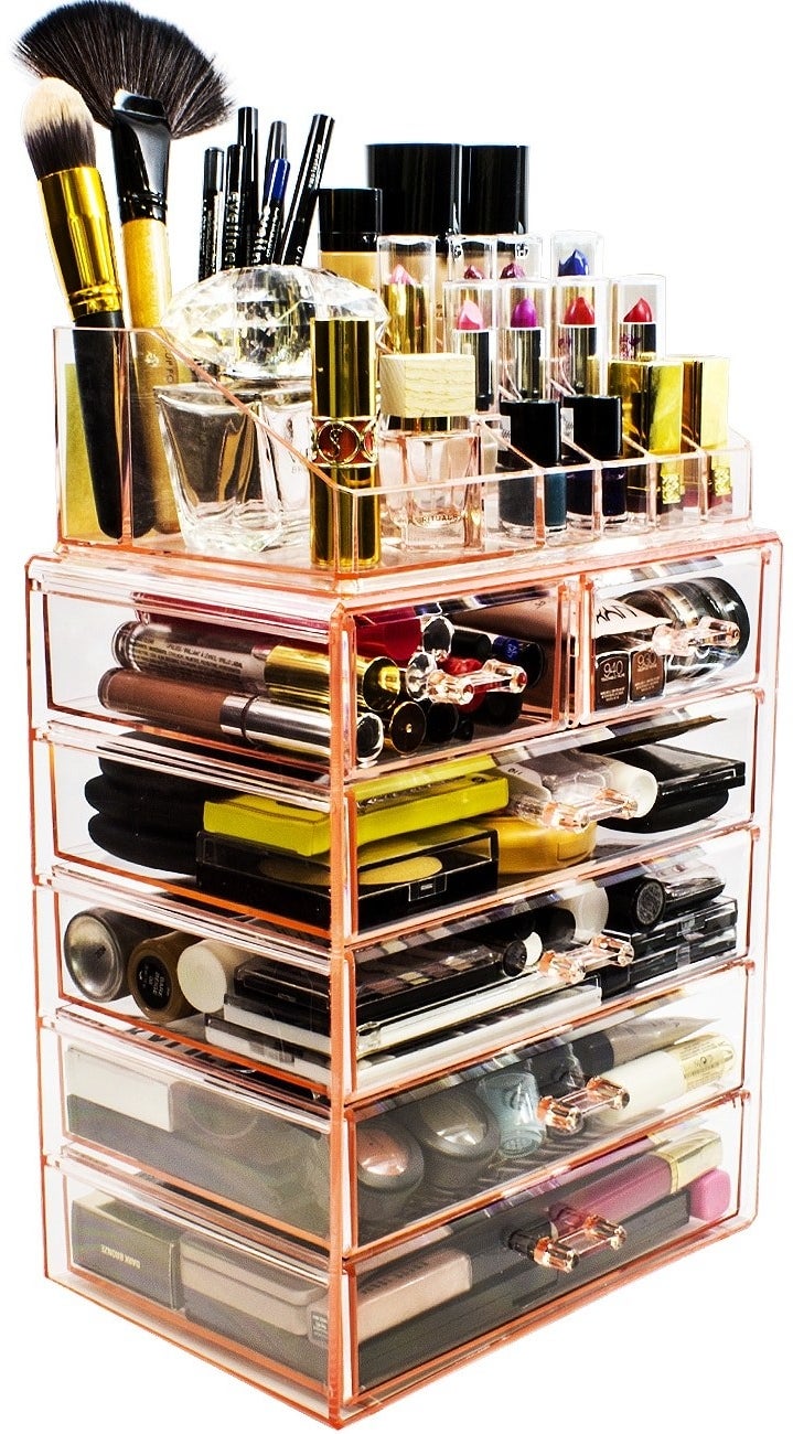 a makeup and jewelry holder in pink holding various makeup accessories