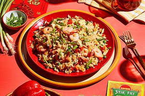 shrimp stir-fried rice on a plate next to fresh red peppers and packet of Sun-Bird stir fry seasoning