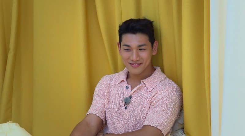 Dong-woo wears a pink shirt and smiles